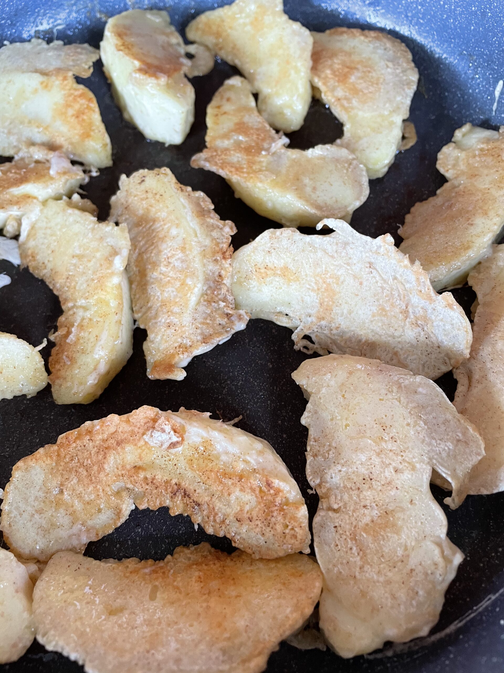 Beignets aux pommes saupoudrés de sucre glace sur une poêle